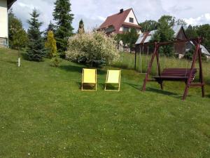 two yellow chairs sitting in the grass next to a bench at Pokoje u Pawloka in Ciche