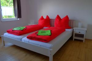 a bed with red pillows and red blankets on it at Ferienwohnungen Ilona Blick in Kelberg