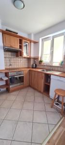 Il comprend une cuisine avec des placards en bois et du carrelage. dans l'établissement Apartament na wydmie u Eli, à Ustka