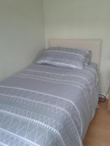 un letto con piumone grigio in una camera da letto di SUNNY SINGLE ROOM in TOOTING a Londra