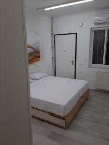Cette chambre blanche comprend un lit et un miroir. dans l'établissement My holiday home, à Rhodes