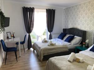 a bedroom with two beds and a desk and a window at Great Polonia Ustka in Ustka