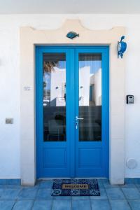 eine blaue Tür in einem weißen Gebäude mit einer Matte davor in der Unterkunft Blue Marine Apartment in Pozzallo