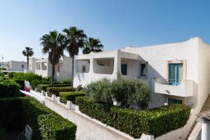 ein weißes Haus mit Büschen und Palmen in der Unterkunft Blue Marine Apartment in Pozzallo