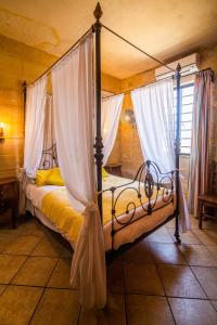 - une chambre avec un lit à baldaquin et des rideaux blancs dans l'établissement Ta' Bertu Host Family Bed & Breakfast, à Ħal Far