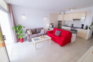 a living room with a red couch and a table at MEDANO4YOU The Harbour Holiday Home in El Médano