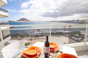 een tafel met een fles wijn op een balkon met uitzicht op de oceaan bij MEDANO4YOU The Harbour Holiday Home in El Médano