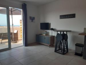 a living room with a table and a television and a door at Studio les pieds dans l'eau vue sur mer in Linguizzetta