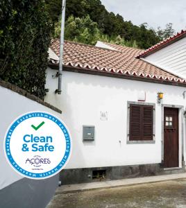 a white house with a sign that reads clean and safe at Casa do Sossego in Furnas