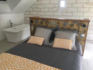 Una cama con almohadas y una bañera en una habitación. en LES PORTES DE BOURGOGNE, en Serbonnes
