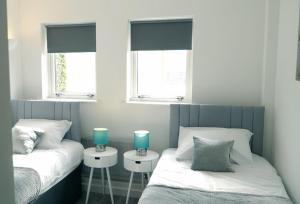 two twin beds in a room with two windows at Blue Apartment, 2 Bedroom with Balcony, Netflix in Peterborough