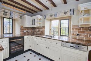 a kitchen with white cabinets and a brick wall at Postman's Knock in Hassop