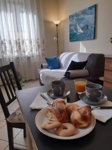 una mesa con un plato de cruasanes y tazas de café en Casa di Tiziana, en Anzio
