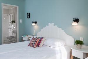 a white bed with a white headboard and a bathroom at 7 Brothers Hotel in Poros