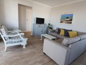 a living room with a couch and a chair at Coral Cottage in Struisbaai