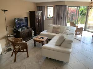 a living room with a white couch and a tv at Boothuis Ter Vaart in Blankenberge