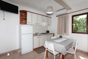 a kitchen with a table and a white refrigerator at Apartments Spavalo in Pag