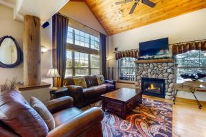 a living room with leather furniture and a stone fireplace at Bear Creek Lodge Townhome in Steamboat Springs