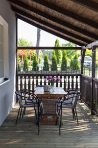 a wooden table and chairs on a balcony with a table and flowers at W Sercu Mazur in Harsz