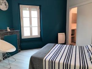 ein blaues Schlafzimmer mit einem Bett und einem Fenster in der Unterkunft Appartement le Flatiron - 4 chambres in Tarbes