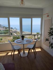 - une salle à manger avec une table, des chaises et des fenêtres dans l'établissement HH Apartamento Algarrobo costa, à Algarrobo-Costa