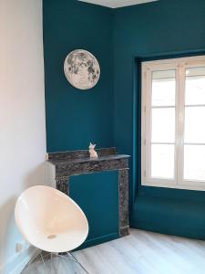 ein blaues Zimmer mit einem weißen Stuhl und einem Fenster in der Unterkunft Appartement le Flatiron - 4 chambres in Tarbes