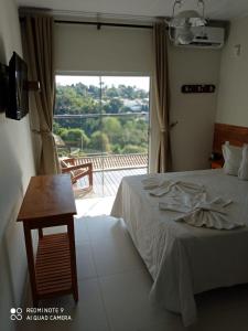 a bedroom with a bed and a view of a balcony at Hotel Escarpas do Lago By San Diego in Capitólio