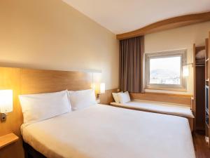 a hotel room with a large bed and a window at Ibis London Luton Airport in Luton +2 photos