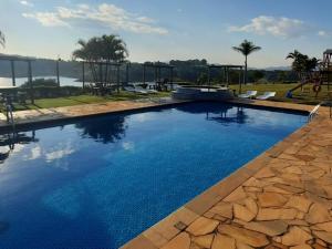 a swimming pool with blue water and a playground at Chalé Represa Recanto Varanda do Sol in Vargem