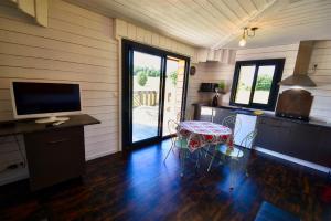 Cette chambre comprend une cuisine avec une table et une télévision. dans l'établissement Chalets CASABELLA, à Casteljaloux