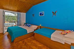 a bedroom with two beds and a blue wall at Villa Mateljan in Zastražišće