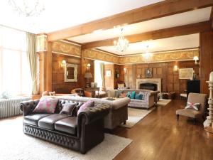 sala de estar con sofá de cuero y chimenea en Bearnock Lodge en Inverness