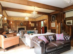 a living room with a leather couch and a fireplace at Bearnock Lodge in Inverness