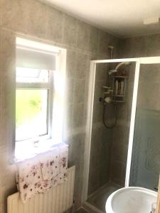 baño con ducha, lavabo y ventana en Murrayville B&B, en Achill Sound