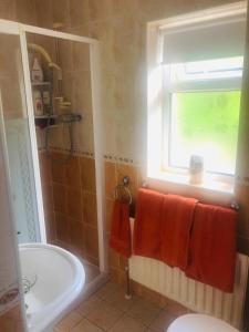 een badkamer met een bad, een raam en oranje handdoeken bij Murrayville B&B in Achill Sound