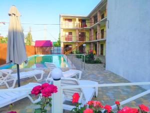 eine Terrasse mit einem Pool, Stühlen und einem Sonnenschirm in der Unterkunft Solnechnaia Dacha in Satoka