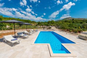 una piscina con sillas y sombrillas en un patio en Villa Pizzelli, en Dubrovnik