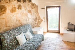 ein Wohnzimmer mit einem Sofa und einer Steinmauer in der Unterkunft Casa nella roccia in Bomarzo