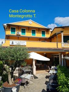 ein Gebäude mit Tischen und einem Sonnenschirm davor in der Unterkunft Casa Colonna in Montegrotto Terme