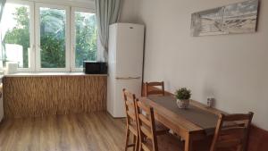 a kitchen with a wooden table and a refrigerator at Pokoje Gościnne u MARCINA- sala zabaw, basen, melex, rowery, grill in Ostrowo