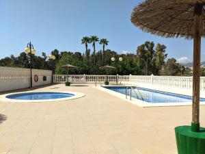 basen z parasolem obok ogrodzenia w obiekcie Cabeho Beach Homes w mieście Calpe