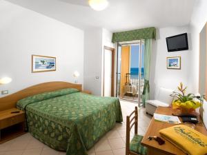 Cette chambre dispose d'un lit, d'un bureau et d'une table. dans l'établissement Hotel Belvedere, à Misano Adriatico