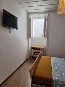 een slaapkamer met een bed en een televisie aan de muur bij Dream Days Guesthouse in Faro