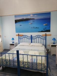 a bedroom with a blue bed with a painting on the wall at Le Case Di Tufo in Favignana