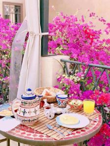 a table with plates and bowls on it with pink flowers at Riad of The Light in Marrakesh