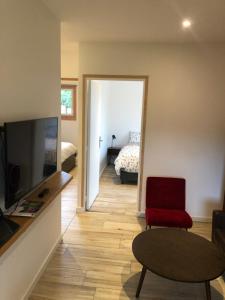 ein Wohnzimmer mit einem TV und einem roten Stuhl in der Unterkunft Gîte entre Golfe du Morbihan et Presqu'île in Surzur