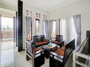 a living room with a table and chairs and windows at OYO 90472 Villa Dua Dua in Tlekung