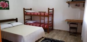 a bedroom with two bunk beds and a table at Cabana da Montanha - Sítio Pasangas in Santo Antônio do Pinhal