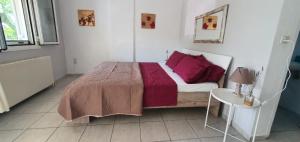 Un dormitorio con una cama con almohadas rojas y una mesa. en Eleni Karouti rooms for rent, en Pteleós