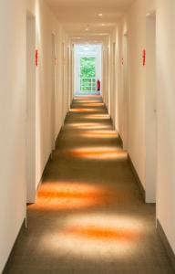 an aisle in an office building with an orange hallway at V-Hotel in Bonn